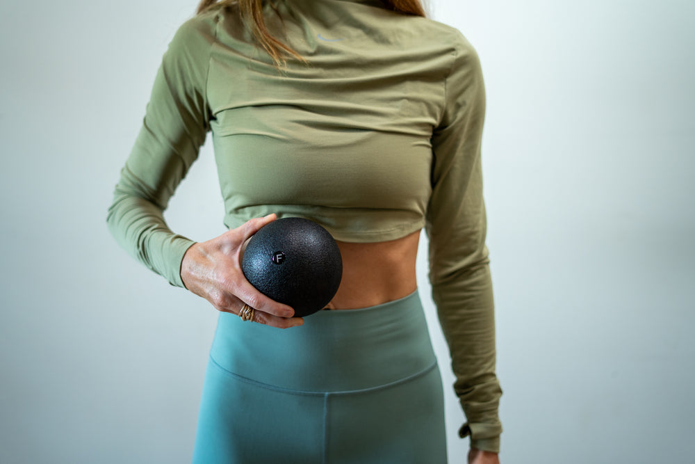 Woman positioning a fascia foam ball for a diaphragm release.
